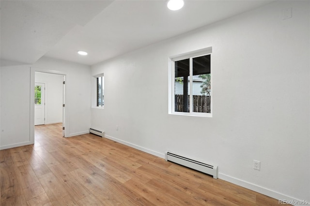 empty room with baseboard heating, light wood finished floors, baseboards, and recessed lighting