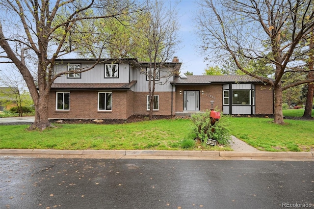view of front facade featuring a front yard, a chimney, and brick siding