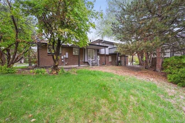 rear view of house featuring a lawn, brick siding, and covered porch