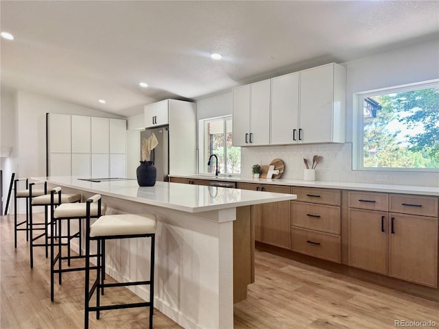 11351 Quivas Way, Denver, CO 80234 - kitchen featuring freestanding refrigerator, tasteful backsplash, light wood-style flooring, a kitchen island, and a breakfast bar area