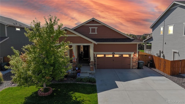 craftsman inspired home with driveway, a garage, a lawn, stone siding, and fence