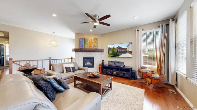 living area featuring recessed lighting, a large fireplace, wood finished floors, visible vents, and baseboards