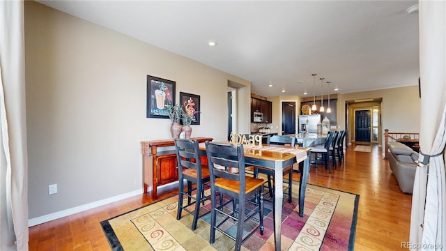 dining space featuring light wood-style floors, baseboards, and recessed lighting