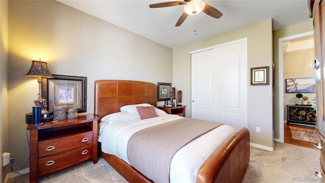 bedroom with a ceiling fan, a closet, light colored carpet, and baseboards