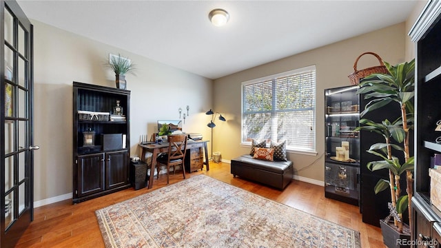 home office with baseboards and wood finished floors