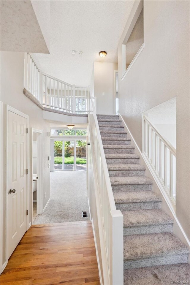 9823 Salford Ln, Highlands Ranch, CO 80126 - stairs featuring wood finished floors, a towering ceiling, and a textured ceiling
