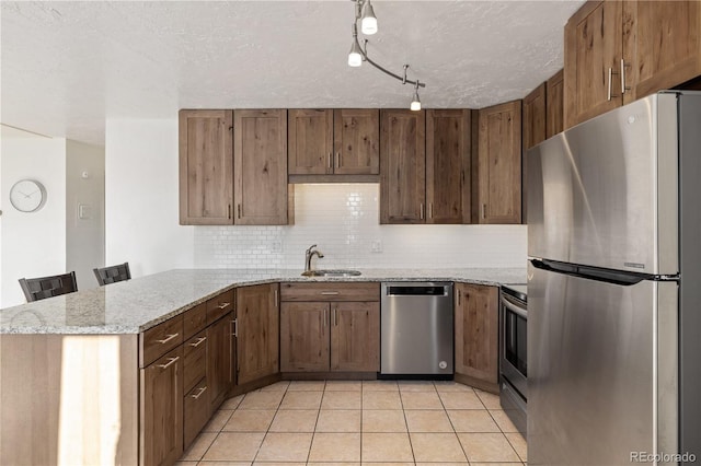 kitchen with light stone countertops, a breakfast bar area, stainless steel appliances, and kitchen peninsula