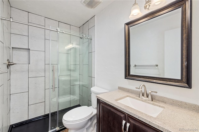 bathroom featuring vanity, a shower with shower door, and toilet