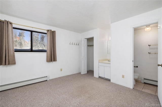 unfurnished bedroom with light carpet, connected bathroom, and a baseboard heating unit