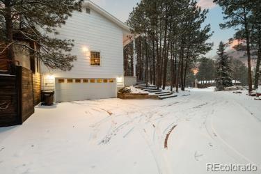 snow covered property featuring driveway and an attached garage