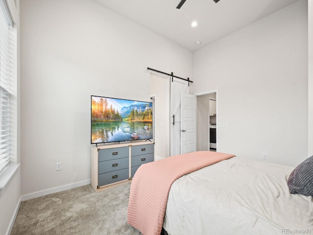 bedroom with a barn door, a towering ceiling, baseboards, light carpet, and recessed lighting