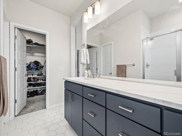 bathroom featuring a stall shower, tile patterned floors, vanity, and a walk in closet