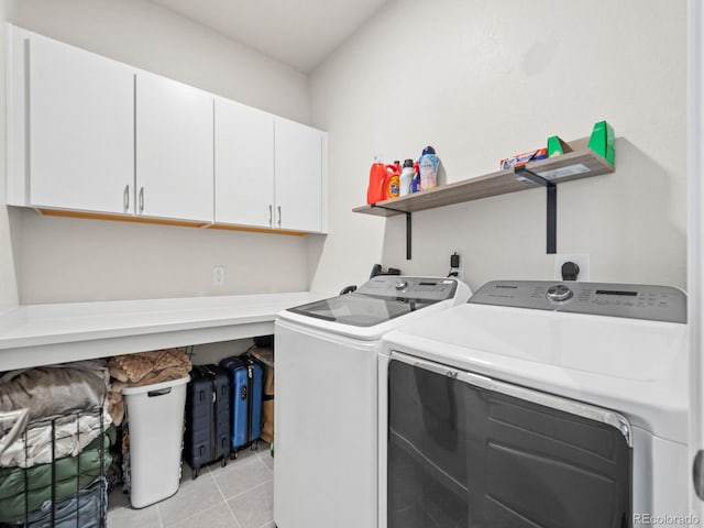 laundry area featuring light tile patterned floors, independent washer and dryer, and cabinet space