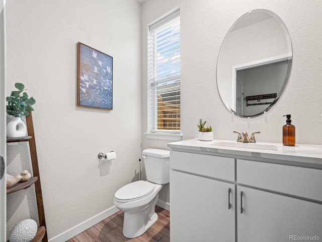 bathroom featuring vanity, toilet, wood finished floors, and baseboards