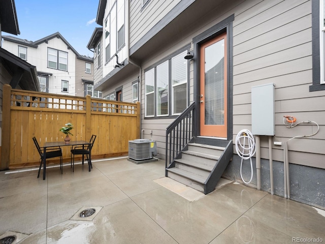 view of patio with outdoor dining space, entry steps, cooling unit, and fence
