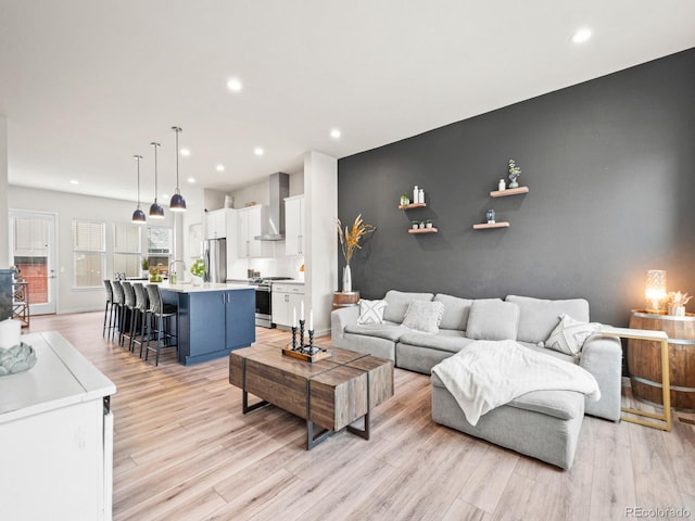 living room with light wood-style floors, recessed lighting, and an accent wall