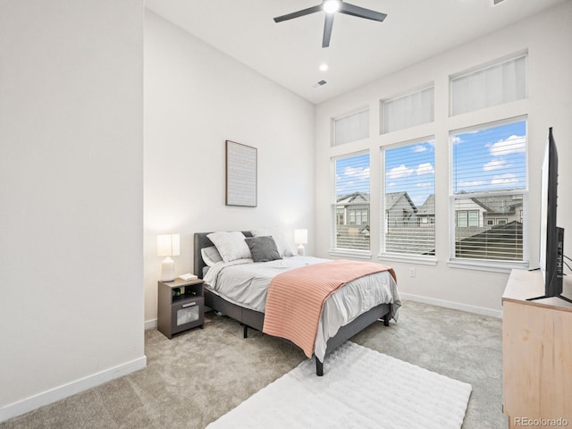 bedroom featuring baseboards, multiple windows, and light colored carpet
