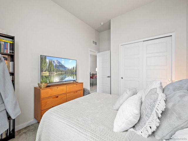 bedroom featuring light colored carpet, a closet, baseboards, visible vents, and a high ceiling