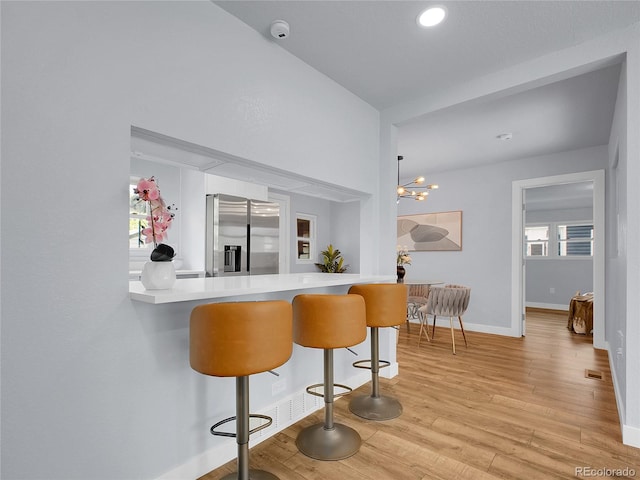 5152 Bryant St, Denver, CO 80221 - kitchen featuring stainless steel fridge with ice dispenser, light wood-style flooring, baseboards, a peninsula, and a breakfast bar