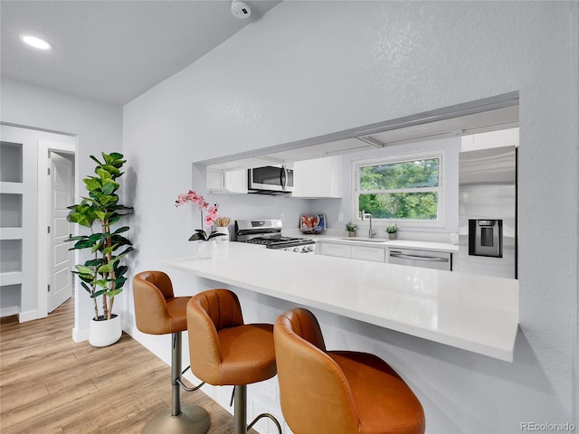 5152 Bryant St, Denver, CO 80221 - kitchen featuring appliances with stainless steel finishes, a peninsula, white cabinetry, a breakfast bar area, and light countertops