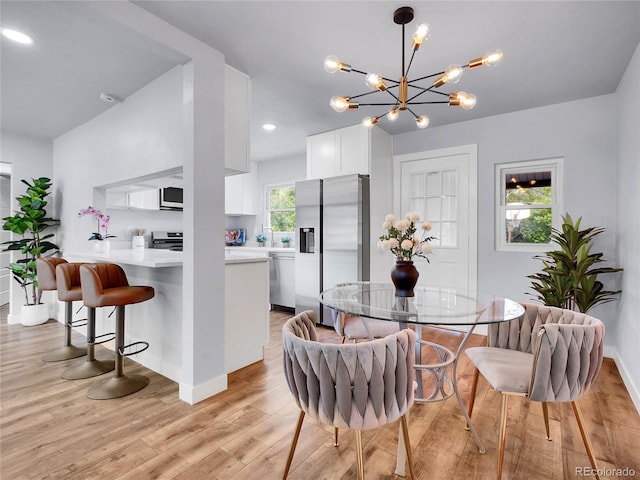 5152 Bryant St, Denver, CO 80221 - dining space featuring light wood-type flooring, a chandelier, and baseboards