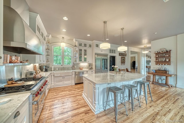 16202 County Road 327, Buena Vista, CO 81211 - kitchen featuring wall chimney range hood, high end appliances, light wood-type flooring, a breakfast bar area, and recessed lighting