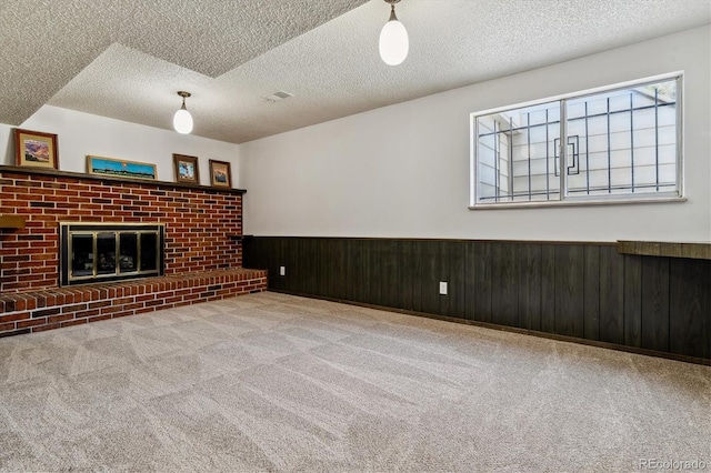13472 W Dakota Ave, Lakewood, CO 80228 - unfurnished living room with carpet flooring, a brick fireplace, a textured ceiling, a wainscoted wall, and visible vents