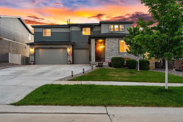 view of front of home featuring stone siding, a front lawn, an attached garage, and driveway