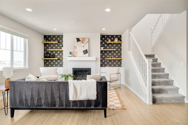 living room with recessed lighting, stairway, a brick fireplace, wood finished floors, and baseboards