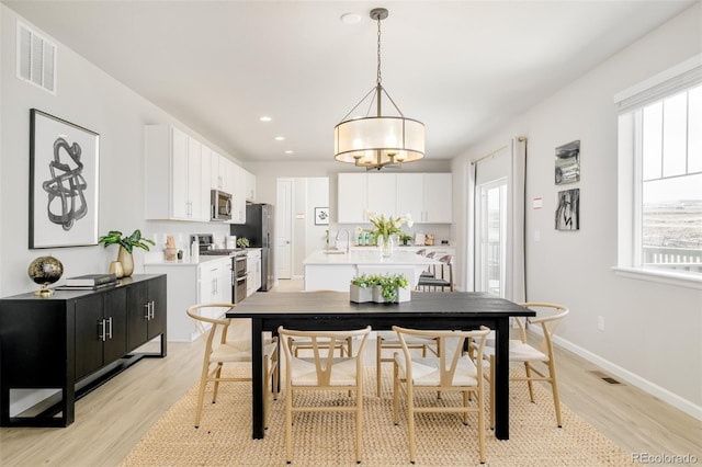 dining area with light wood finished floors, visible vents, and baseboards