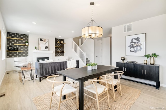 dining area with visible vents, light wood-style floors, stairs, a brick fireplace, and recessed lighting