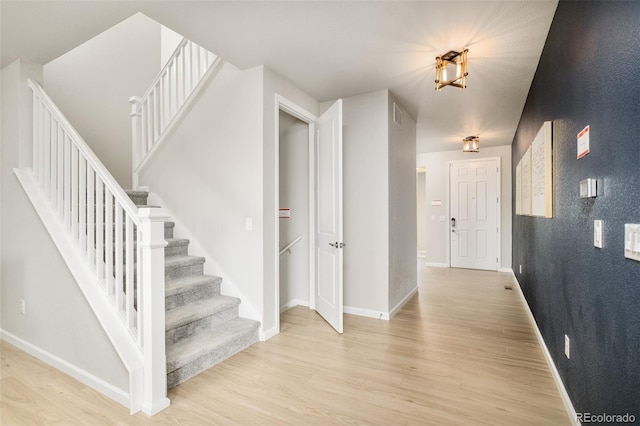 interior space featuring baseboards, visible vents, light wood finished floors, and stairs