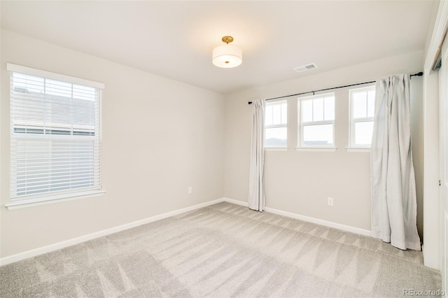 spare room with baseboards, visible vents, and light colored carpet