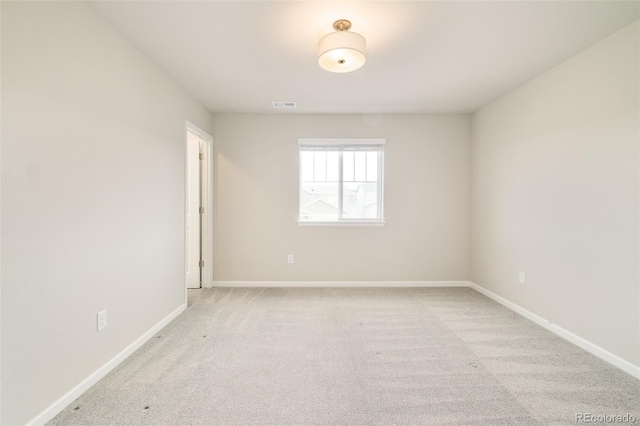 unfurnished room with visible vents, light colored carpet, and baseboards