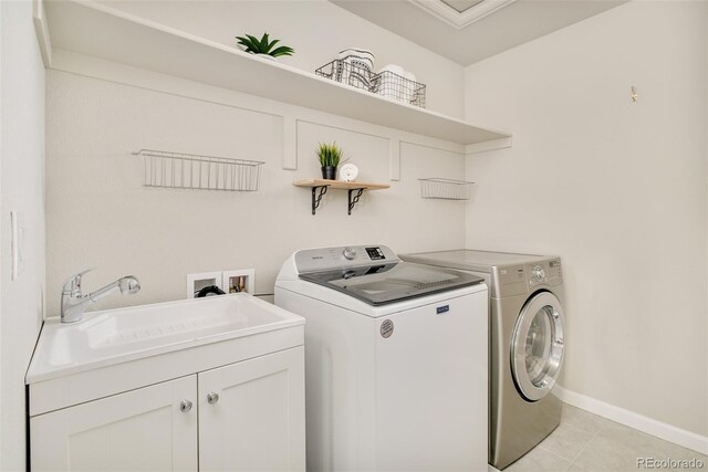 clothes washing area featuring light tile patterned floors, a sink, baseboards, cabinet space, and washing machine and clothes dryer