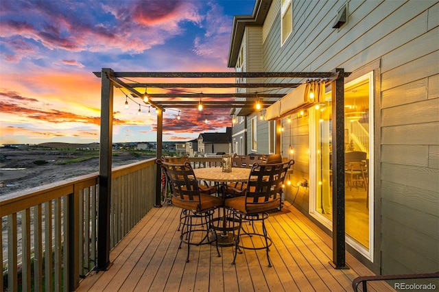 deck at dusk with outdoor dining space and a pergola