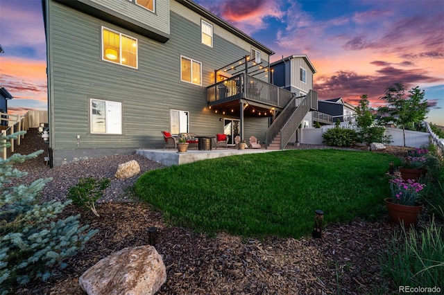 rear view of house featuring stairway, a yard, fence, a wooden deck, and a patio area