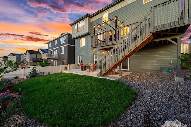 rear view of property with stairs, fence, a lawn, and a patio