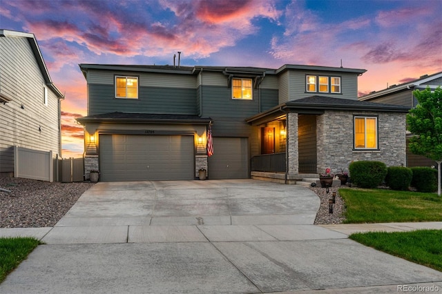 view of front facade featuring stone siding, concrete driveway, fence, and an attached garage