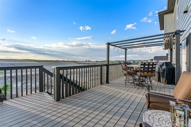 wooden terrace with outdoor dining space, area for grilling, and a pergola