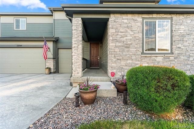 view of exterior entry with driveway and an attached garage