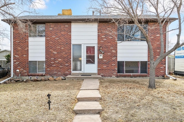 bi-level home with brick siding and a chimney