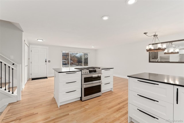 kitchen with decorative light fixtures, range with two ovens, light hardwood / wood-style flooring, white cabinets, and a chandelier