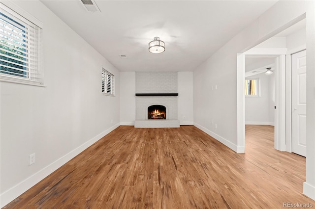 unfurnished living room featuring light hardwood / wood-style floors, a brick fireplace, and ceiling fan