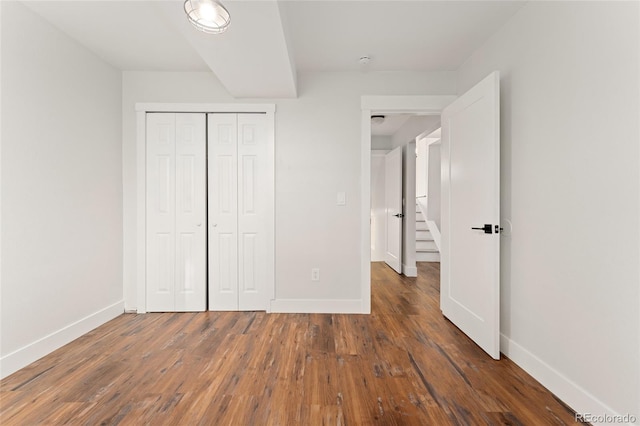 unfurnished bedroom with a closet and dark wood-type flooring