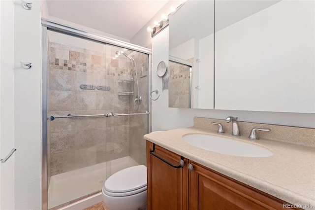 bathroom featuring vanity, a shower with shower door, and toilet