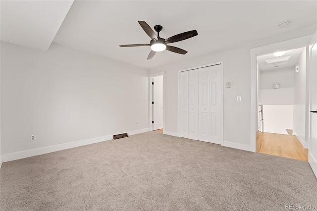 unfurnished bedroom featuring ceiling fan, a closet, and light colored carpet