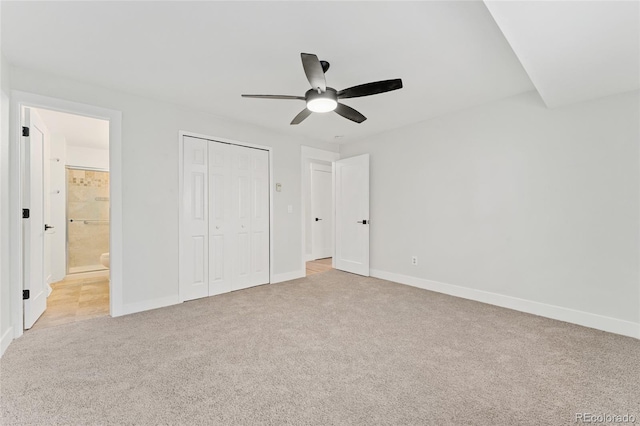 unfurnished bedroom featuring ensuite bath, ceiling fan, a closet, and light colored carpet