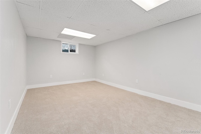 basement featuring a paneled ceiling and carpet