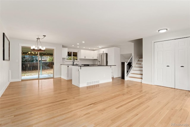 unfurnished living room with light hardwood / wood-style floors, sink, and an inviting chandelier